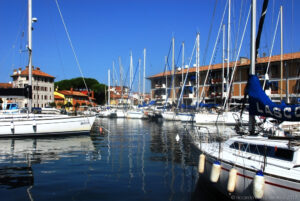 Il porto di Grado con la sua tipica forma ad Y voluta dagli austro-ungarici, rappresenta anche il salotto cittadino sul mare con bar, caffè, ristoranti negozi e ovviamente barche a vela.