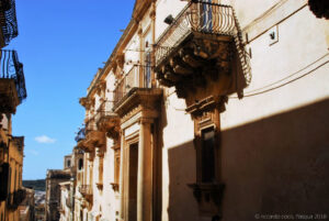 La facciata di Palazzo Nicolaci di Villadorata a Noto; dove si svolge ogni anno l'Infiorata, in stile barocco, è caratterizzata da un ampio portale fiancheggiato da due grandi colonne ioniche e sormontato da un balcone, nonché da sei balconi più piccoli (tre per lato), sorretti da mensoloni scolpiti uno in modo diverso dall'altro, con le sembianze di leoni, bambini, centauri, cavalli alati, chimere e sirene